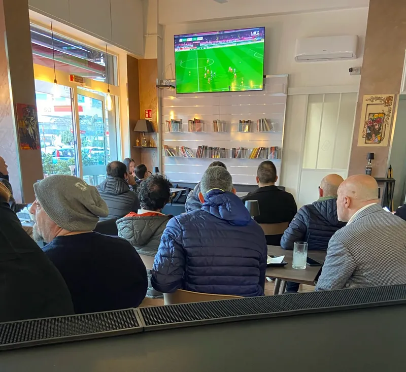 La sala di Danna piena di clienti che guardano una partita di calcio sul maxischermo